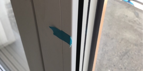 Zbliżenie na ramę okienną, na której zaznaczono niebieską taśmą uszkodzenie, co zaznaczył nasz specjalista podczas odbioru technicznego w Łodzi.