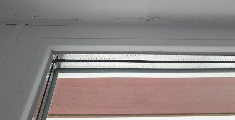 Ujęcie obejmujące ramę okienną i ścianę ponad nią. Na ścianie widoczna popękana obróbka okna, co odkryto na odbiorze technicznym w Olsztynie.