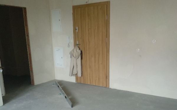 Ujęcie drzwi wejściowych wraz z wylewką. Widoczna na zdjęciu nierówność zaznaczona łatą budowlaną, co zostało sprawdzone przez naszego inżyniera podczas odbioru technicznego w Opolu.